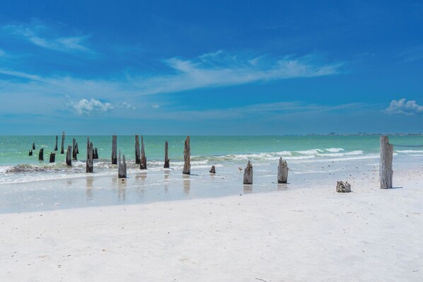 Een strand met houten palen en een helderblauwe lucht.