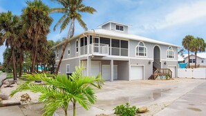 A two-story house with a balcony, a garage, and a covered porch. - 🏖️Shared Pool | Steps to the Beach | Awesome Location | Beach Villa B🏖️ (Fort Myers Beach)