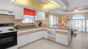 A modern kitchen with a central island, white cabinetry, and a built-in dishwasher. - 🏖️Shared Pool | Steps to the Beach | Awesome Location | Beach Villa B🏖️ (Fort Myers Beach)