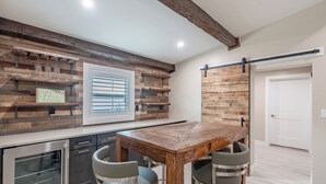 Een moderne keuken met een houten tafel, barstoelen, inbouwplanken en een schuifdeur in boerderijstijl.