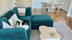 A living room with teal sofas, a coffee table, and a dining area with a white table and chairs. - Bright & Airy 2-bed, 2.5-bath house in historic Germantown, Nashville (Nashville)