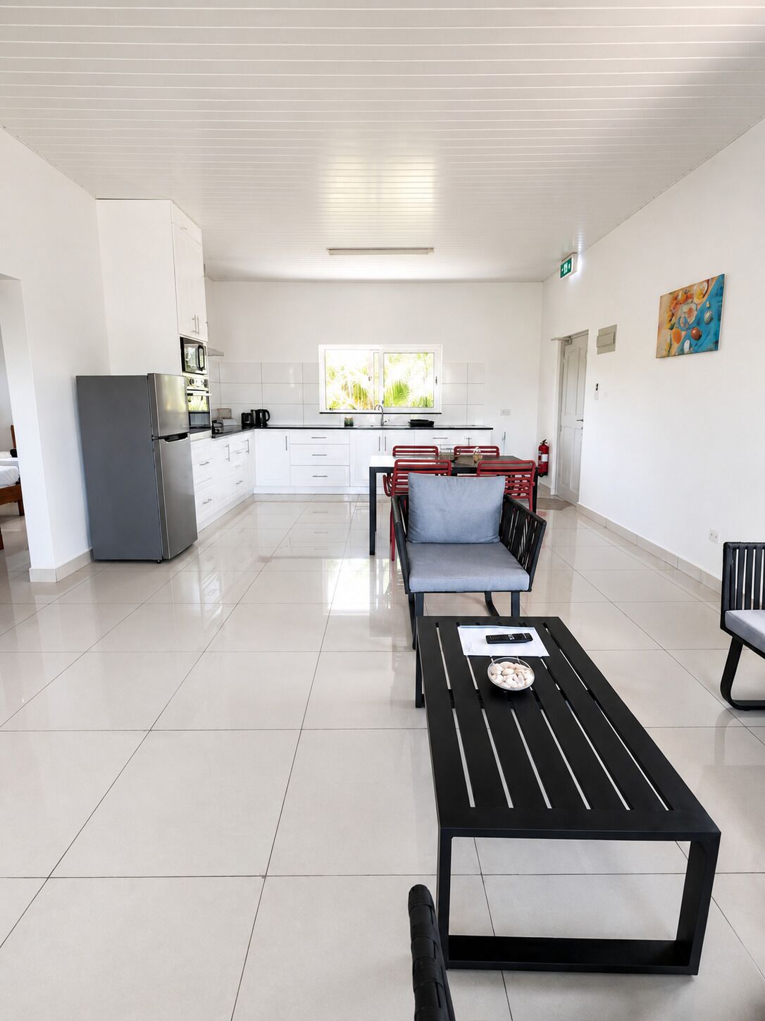 A spacious living area with a dining table, a sofa, and a kitchen in the background.