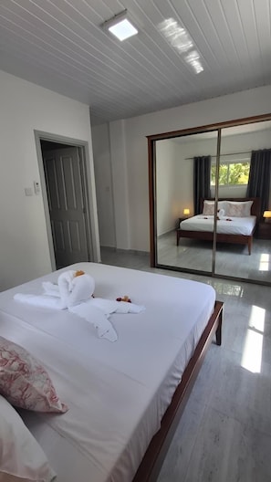 Een hotelkamer met een groot bed, een schuifglasdeur naar een balkon en een houten plafond.
