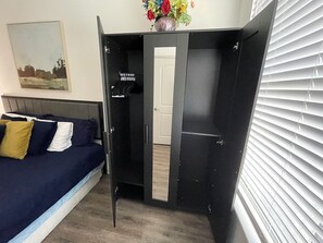A bedroom with a bed, a wardrobe, and a window with blinds.