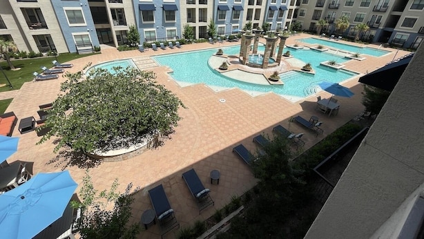 En hotelgård med swimmingpool, liggestole og en central fontæne.