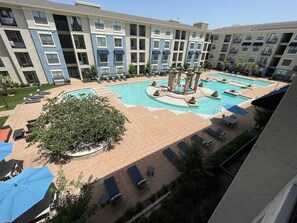 A hotel courtyard with a swimming pool, lounge chairs, and a central fountain.