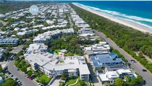 Vista aérea de una zona residencial costera con casas modernas, una playa y un cielo despejado.