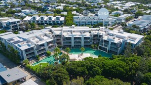 Un moderno complejo residencial con varias torres, un patio central con piscina y un llamativo letrero 'CHG'.