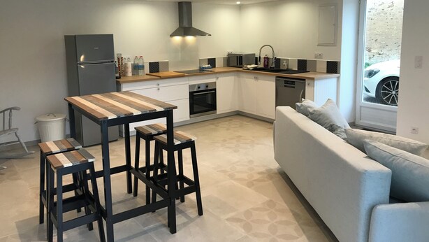 Eine moderne Küche mit Holztisch und Barhocker, inklusive eingebautem Ofen und Geschirrspüler.