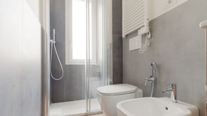A modern bathroom with a glass shower enclosure, a toilet, and a sink.