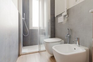 A modern bathroom with a glass shower enclosure, a toilet, and a sink.