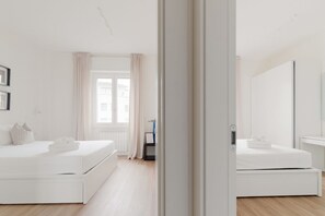 A modern bedroom with a large window, a bed with a white mattress and pillows, and a bedside table. - GuestHost - Modern Apartment Lambrate Milano (Milan)