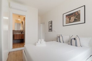 Een hotelkamer met een bed, een badkamer met spiegel en een ingelijst schilderij aan de muur.