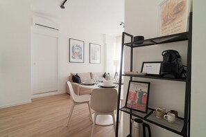 Un espacio habitable moderno y minimalista con zona de comedor, sofá, mesa de centro y estantería.