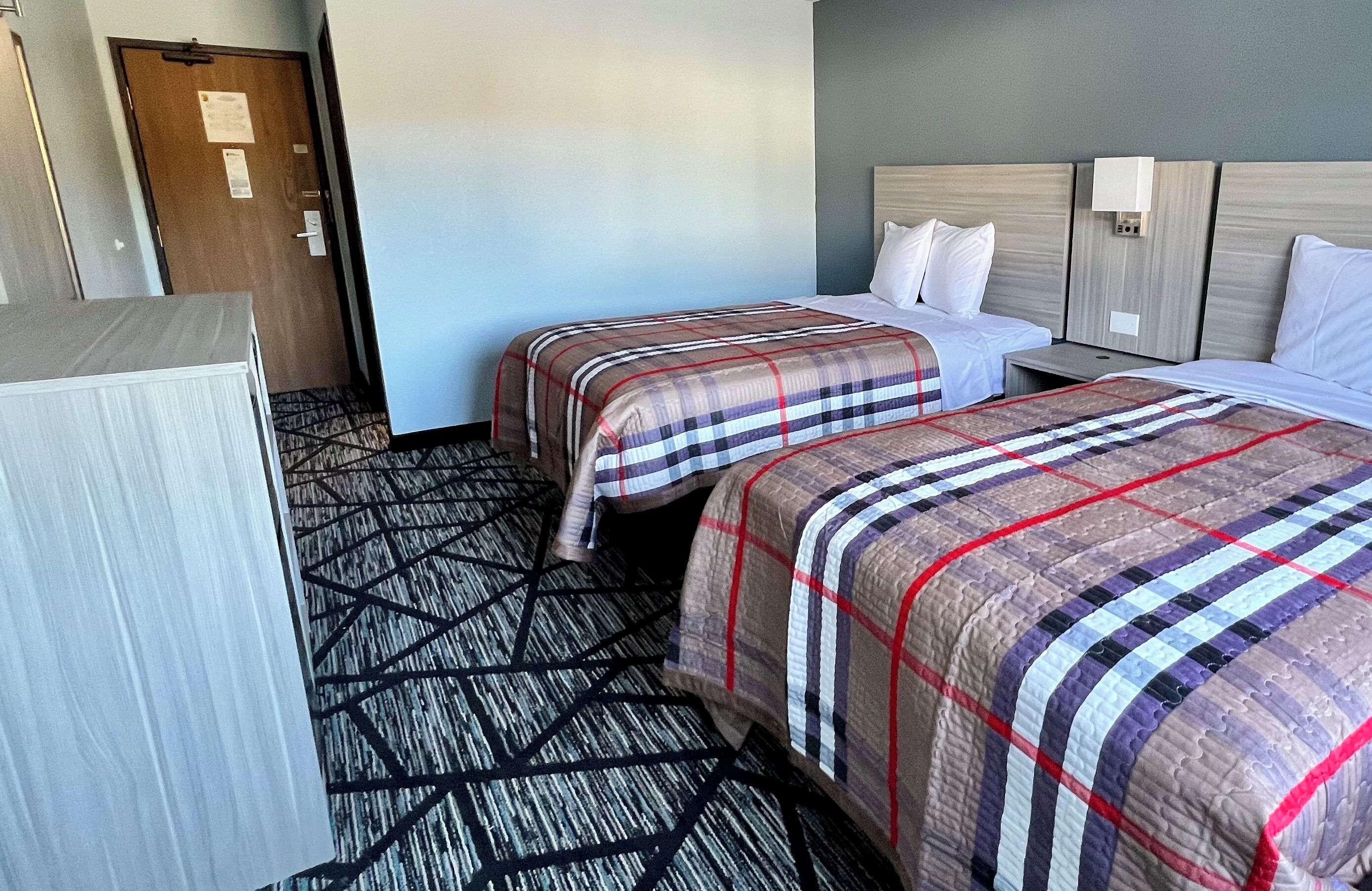 Een hotelkamer met twee bedden, een bureau en een kledingkast.