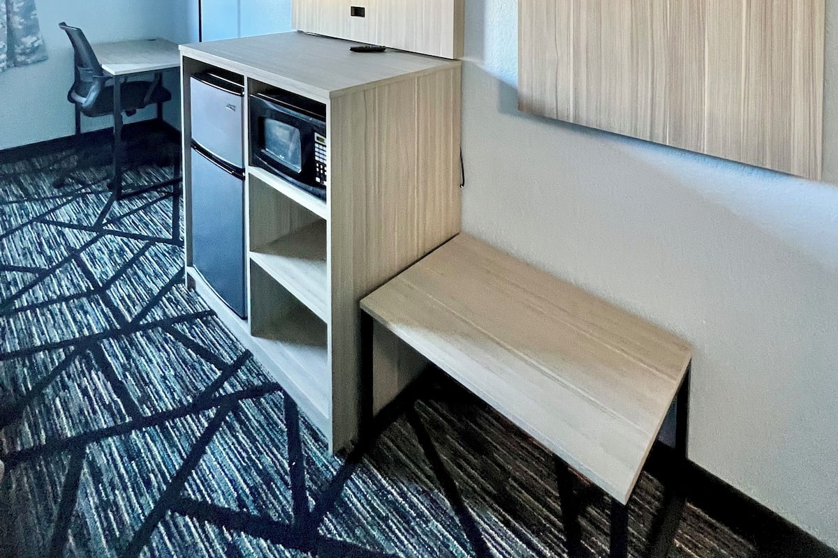 Une chambre d’hôtel équipée d’un bureau, d’une chaise, d’une télévision, d’une armoire et d’un tapis à motifs.