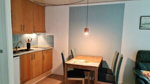 A compact kitchen with wooden cabinets, a dining table with chairs, and a pendant light. - Sea sun (Nørre Nebel)