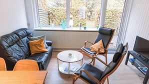 Un salon moderne avec un canapé en cuir, deux fauteuils, une table basse et un meuble pour la télévision.