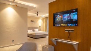 Una habitación de hotel moderna con una cama, un televisor montado en la pared y una pequeña mesa con un control remoto.