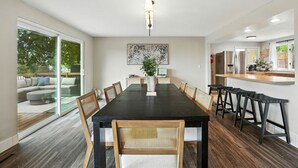 A modern dining area with a long table, chairs, and a bar area. - The South Perry Perch ~ 5BD Family Retreat (Spokane)