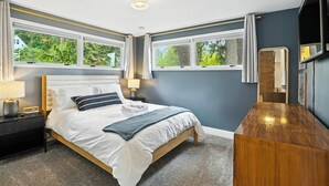 A bedroom with a bed, bedside tables, a dresser, and a TV. - The South Perry Perch ~ 5BD Family Retreat (Spokane)