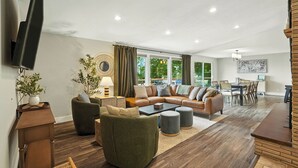 A modern living room with a sectional sofa, a coffee table, and a dining area with a table and chairs. - The South Perry Perch ~ 5BD Family Retreat (Spokane)
