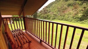 A wooden deck with a bench, surrounded by a wooden railing, overlooking a lush green landscape. - Cabin in Cerro Punta  6BR, Fireplace, Hiking (Cerro Punta)