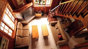 A cozy, wooden-furnished living room with a fireplace, a sofa set, and a wooden coffee table. - Cabin in Cerro Punta  6BR, Fireplace, Hiking (Cerro Punta)