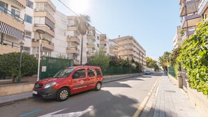 Una furgoneta roja estacionada en una calle urbana flanqueada por edificios de varios pisos.