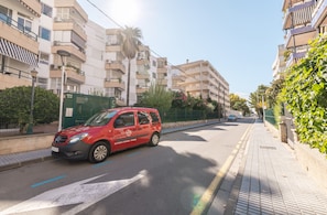 A red van parked on a city street with multi-story buildings on either side.