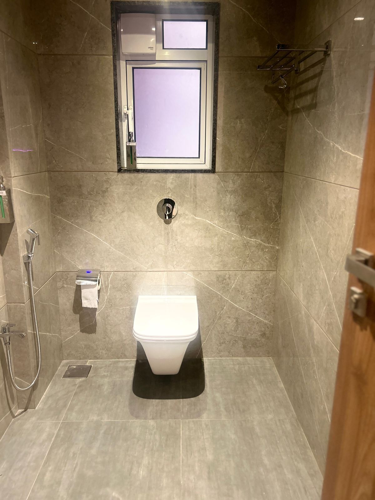 Un bagno moderno e piccolo, con il water, una doccia e un porta asciugamani.