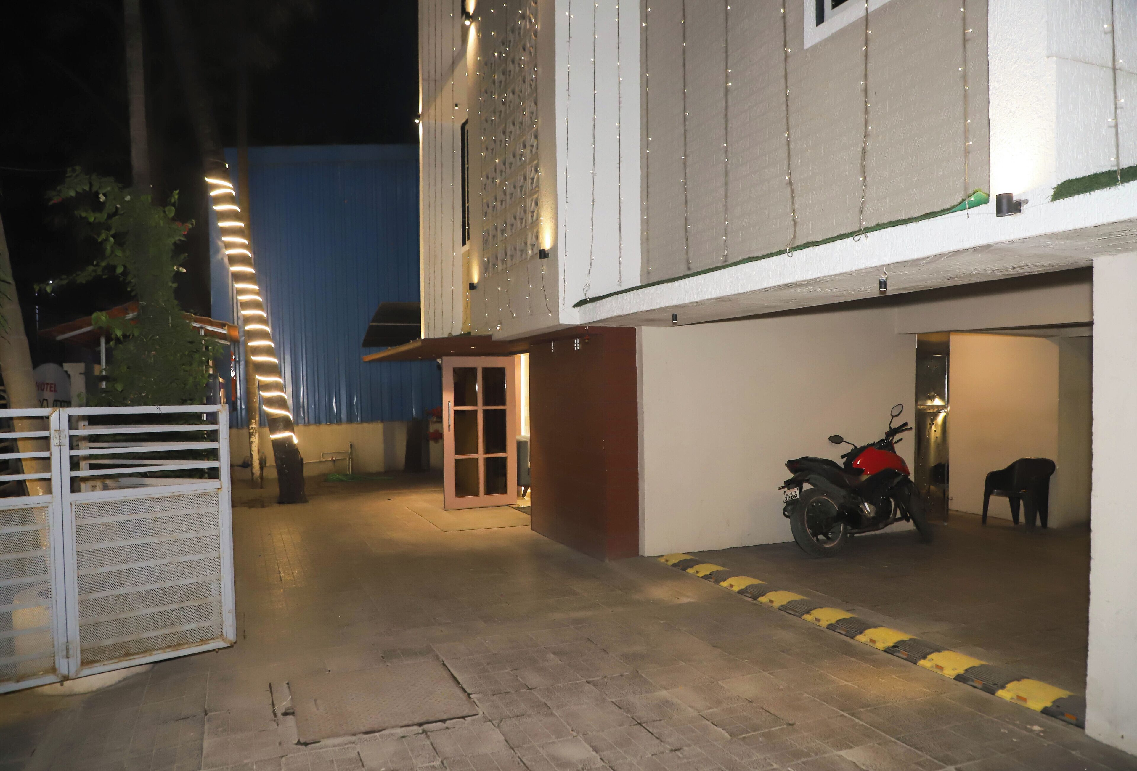 A parking area with a motorcycle, a gate, and a building entrance.