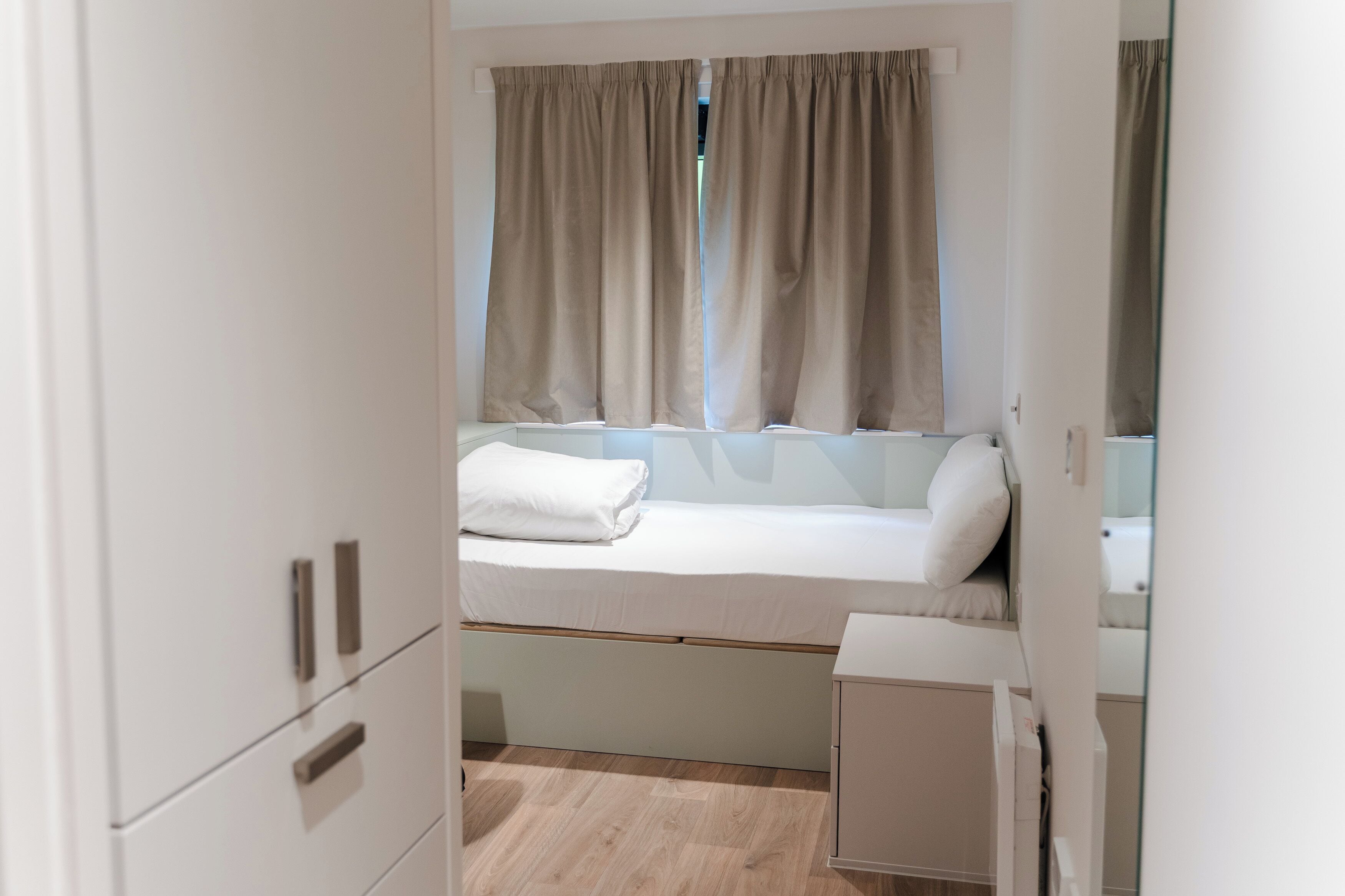 A compact bedroom with a single bed, a small bedside table, and a wardrobe.