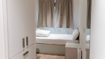 A compact bedroom with a single bed, a small bedside table, and a wardrobe.