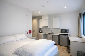 A modern hotel room with a bed, kitchenette, and a window with curtains. - Destiny Student - Burnet Point (Edinburgh)