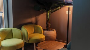 Une pièce avec deux chaises jaunes, une table ronde en bois et une grande plante en pot.