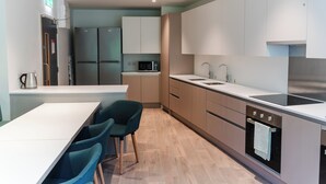 Une cuisine moderne avec un coin repas, comprenant un réfrigérateur, un four à micro-ondes, un évier et un four, tous en acier inoxydable.