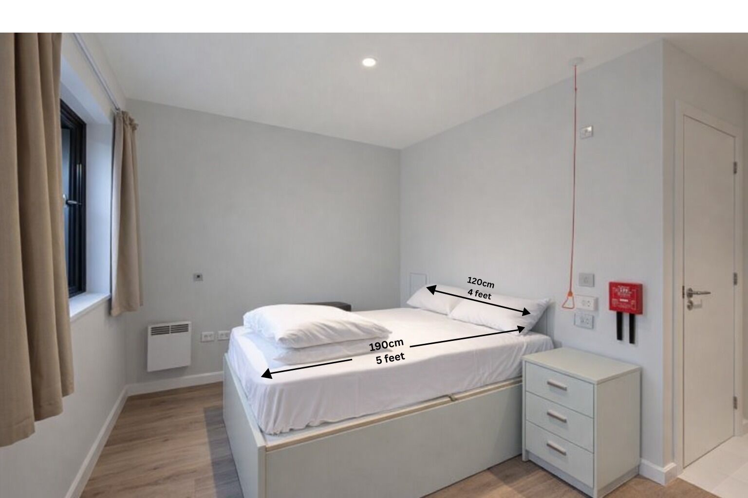 A bedroom with a bed measuring 120cm by 190cm, a white bedside table, and a window with curtains.