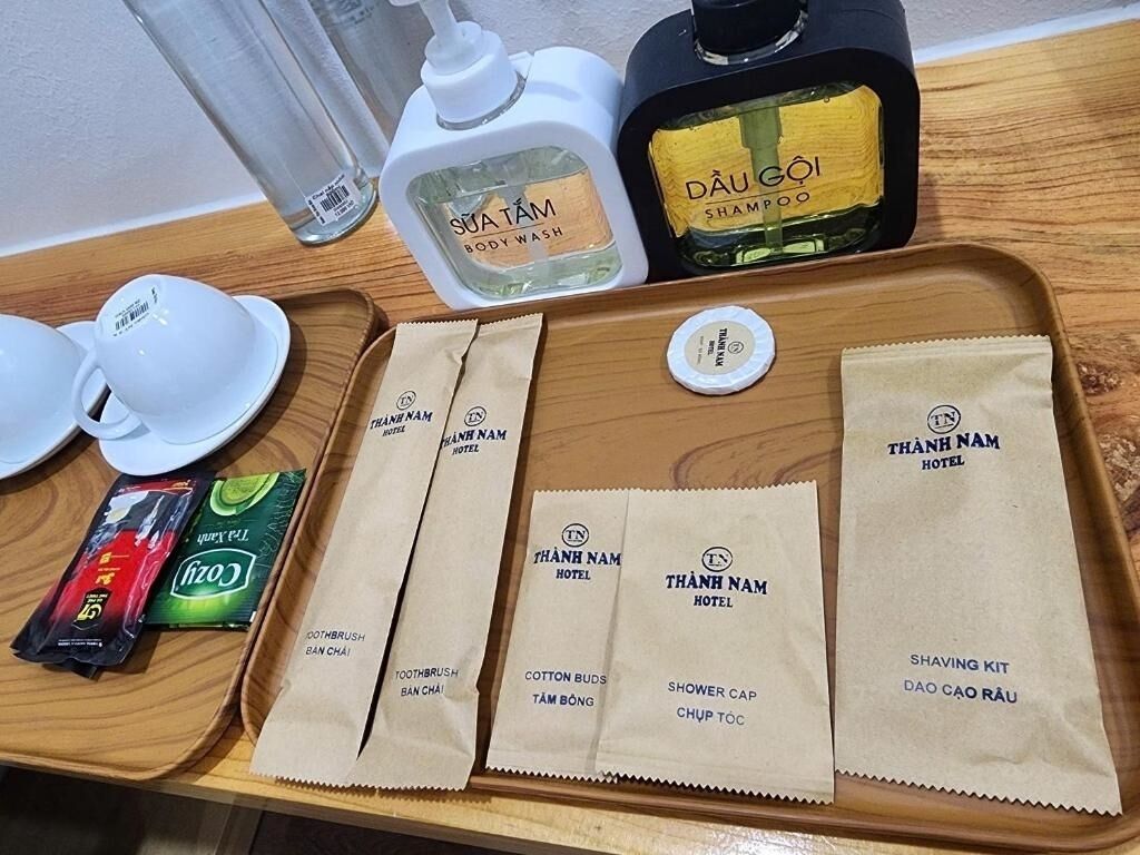 A tray with toiletries including body wash, shampoo, toothbrushes, cotton buds, a shower cap, and a shaving kit.
