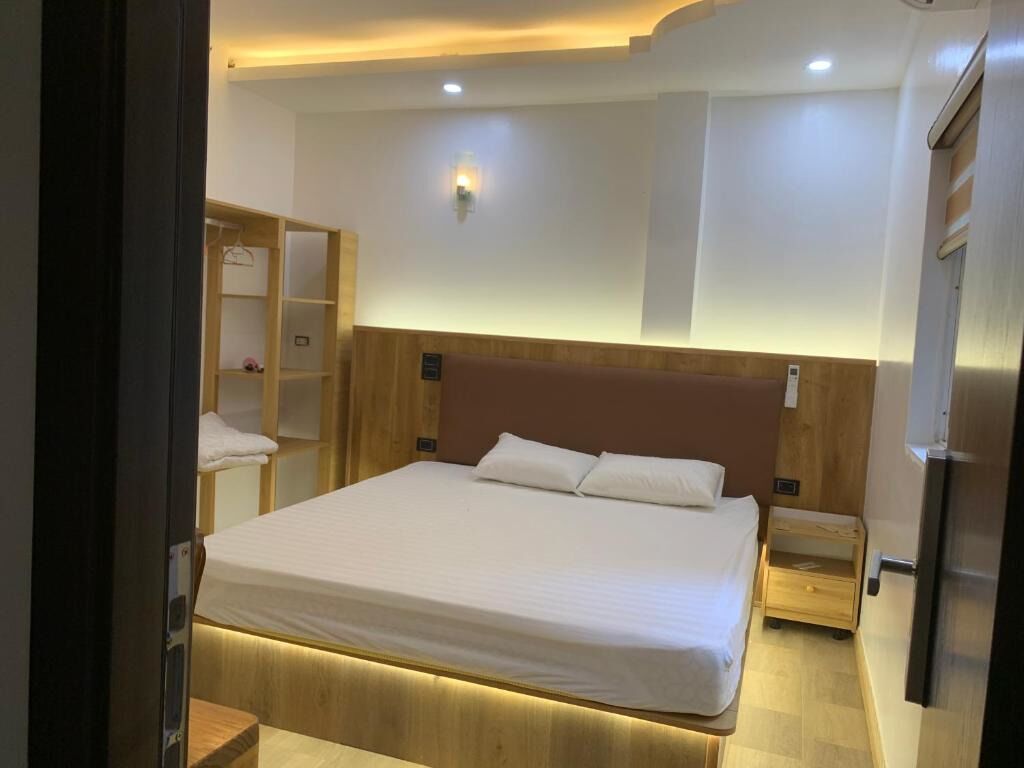 Een hotelkamer met een groot bed, een houten hoofdbord, nachtkastjes, een kledingkast en een ingebouwde televisie.