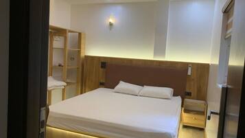 Een hotelkamer met een groot bed, een houten hoofdbord, nachtkastjes, een kledingkast en een ingebouwde televisie.