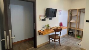 A compact hotel room with a wooden desk, a chair, a television, and a built-in shelf with storage. - Thành Nam Hotel (Dien Bien Phu)