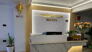 A reception desk with a marble front and a wooden accent. The reception area has a sign that reads "THANH NAM HOTEL". - Thành Nam Hotel (Dien Bien Phu)