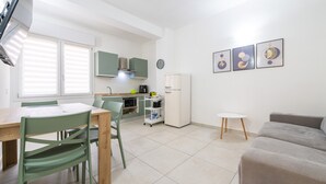 A modern kitchen with a dining table and chairs, a refrigerator, a microwave, and a small cabinet.