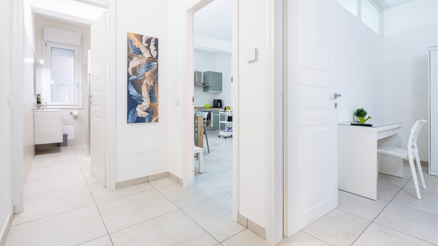 A modern interior with a hallway leading to a kitchen and a dining area.
