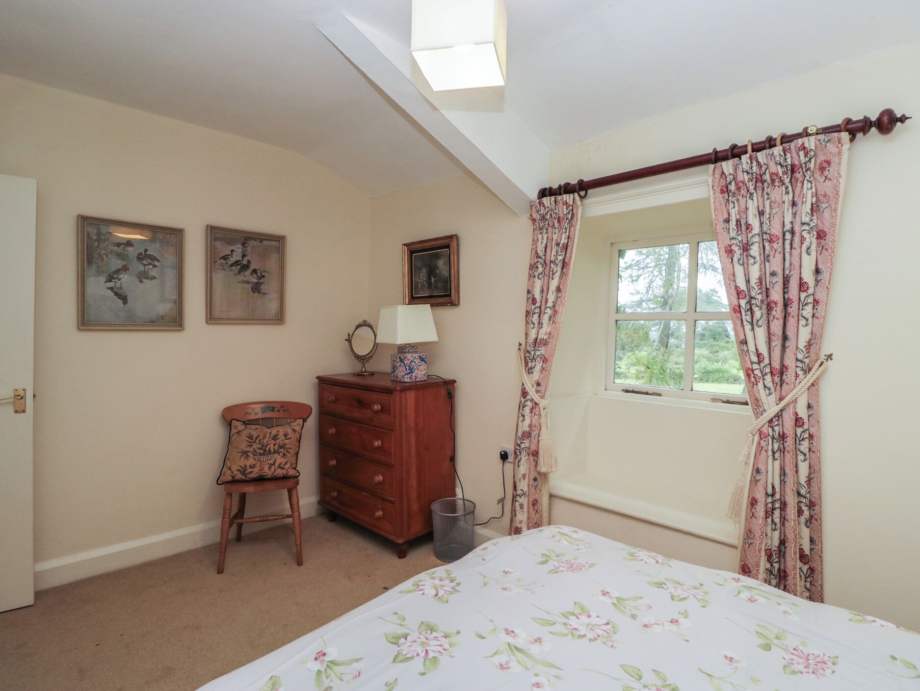 A bedroom with a bed, a dresser, a chair, and a window with curtains.