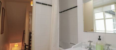Une salle de bain avec un lavabo blanc, un miroir et un rideau de douche.