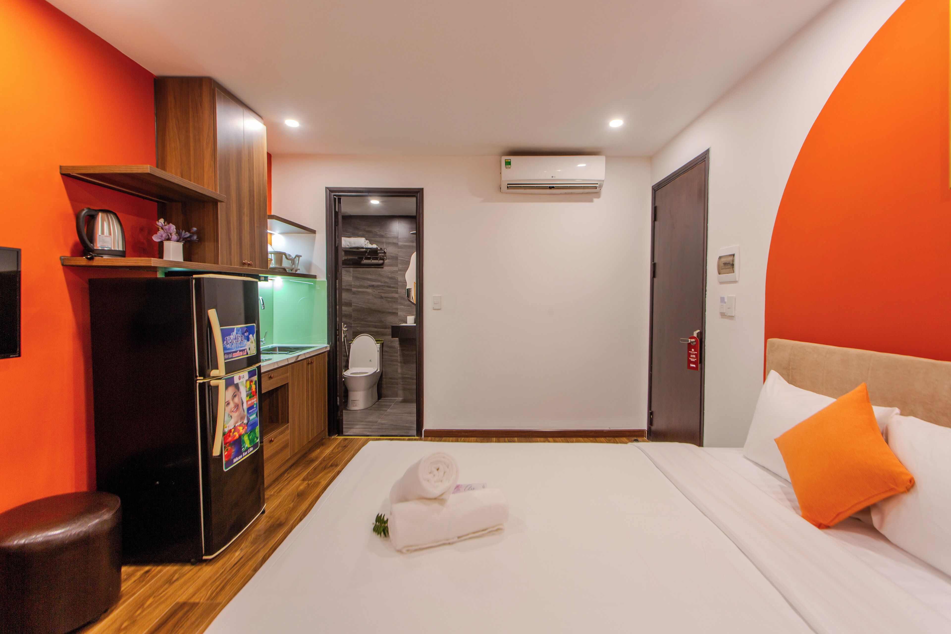 A hotel room with a bed, a refrigerator, a sink, and a shower area.