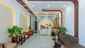 A hotel reception area with a modern design, featuring a reception desk, seating arrangements, and decorative plants. - Fusia Hotel & Apartment (Da Nang)