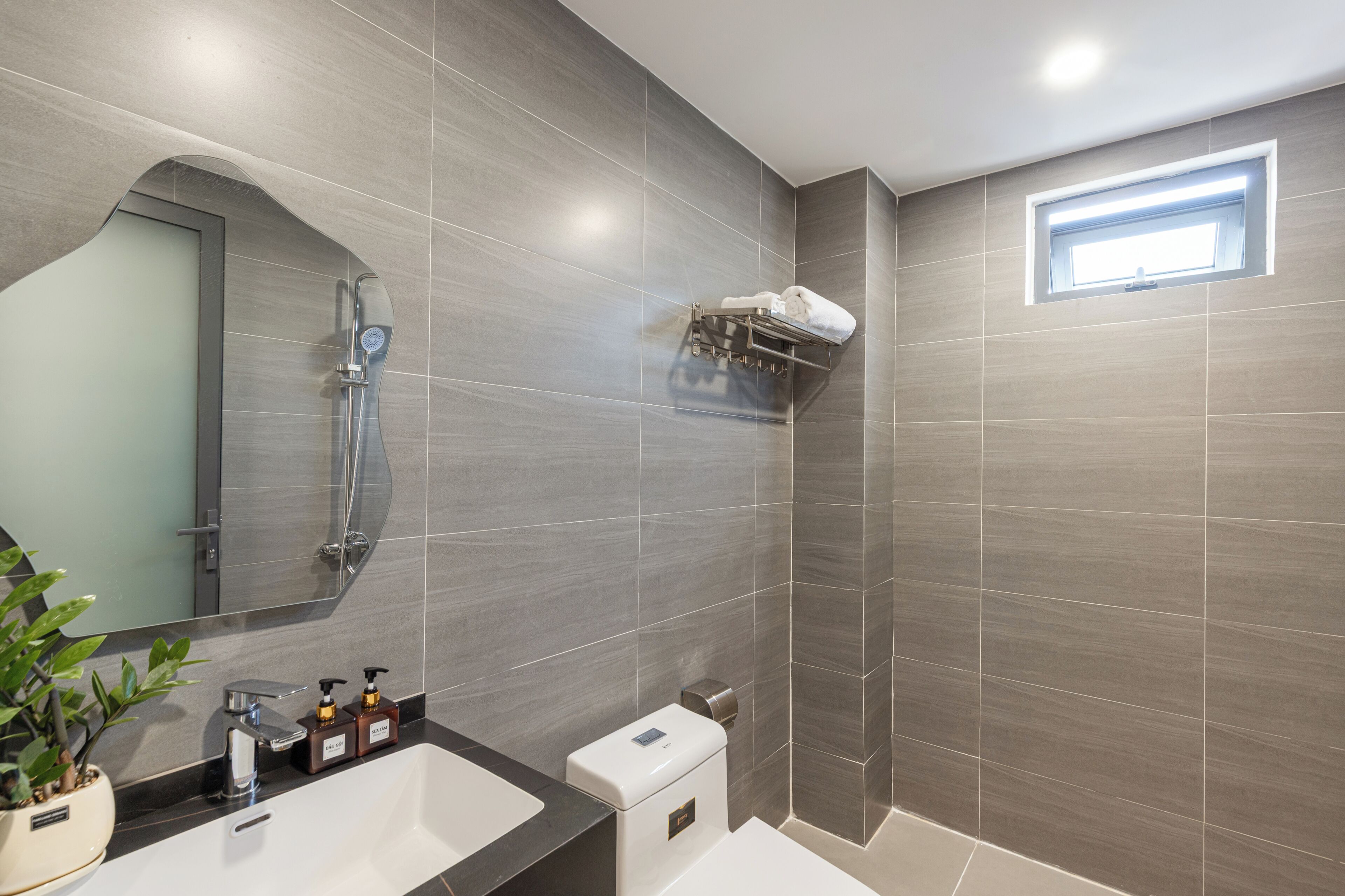 A modern bathroom with a shower, a sink, a toilet, and a mirror.